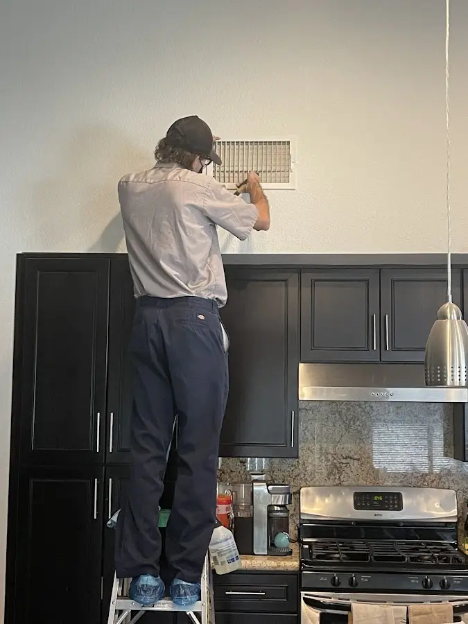 Technician inspecting an air vent during HVAC service in Massapequa Park